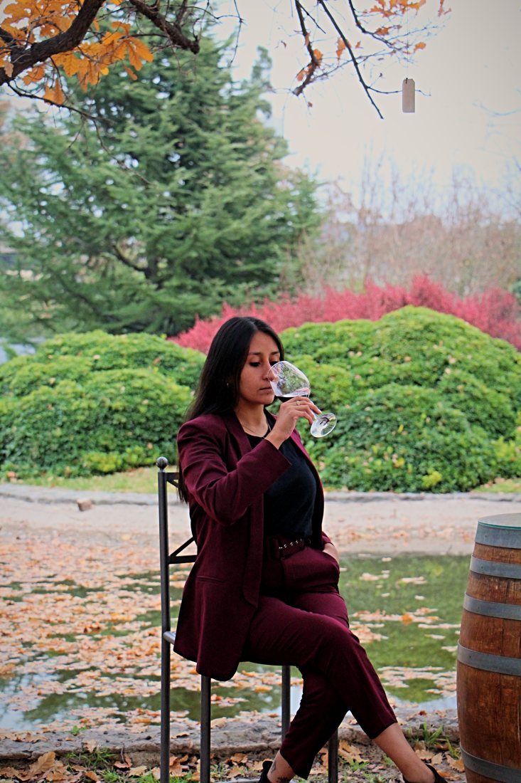 Daiana Cortez, gerente de hospitalidad de Sin Etiquetas, catando vino en un jardín otoñal