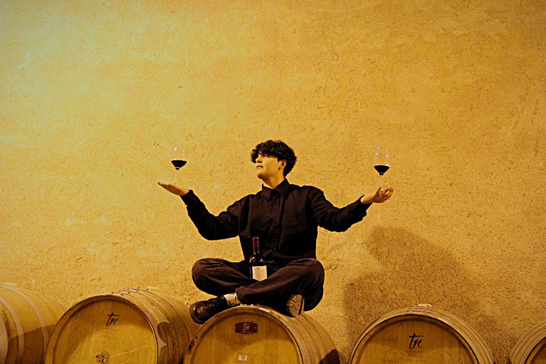 Haise Gimenez, sommelier de Sin Etiquetas, con dos copas de vino tinto en una bodega